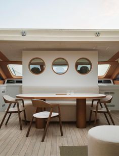 the interior of a boat with round windows and wooden tables, chairs, and couches