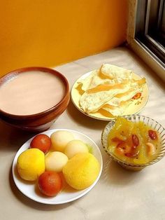 there are three plates with fruit on the table next to some cups and saucers