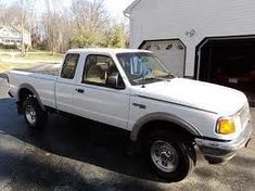 a white pick up truck parked in front of a barn