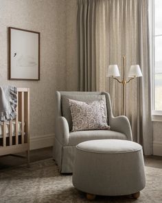 a baby's room with a chair, crib and lamp