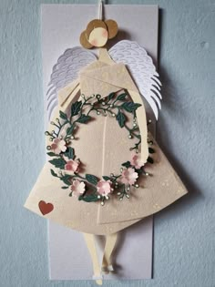 a card with an angel holding a wreath on it's back and two wings