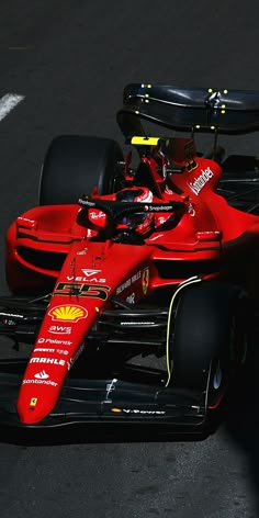 a red ferrari racing car driving on a race track with the driver sitting in the front