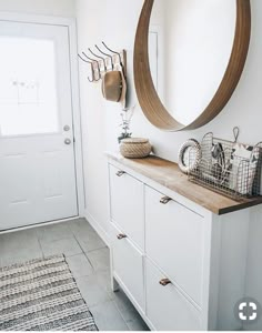 a white and wood entryway with a round mirror on the wall