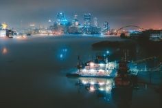 a boat floating on top of a body of water next to a city at night