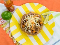 a plate topped with a tortilla covered in shredded cheese next to a lime