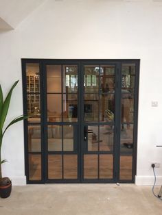 an empty room with glass doors and a potted plant