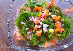 a glass bowl filled with salad on top of a wooden table