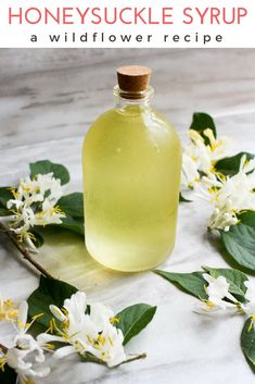 a bottle filled with liquid sitting on top of a table next to white and yellow flowers