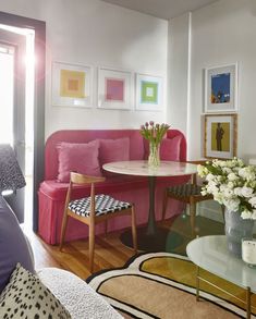 a living room filled with furniture and flowers on top of a glass table in front of a pink couch