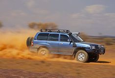 a truck driving through the desert with dust coming off it's tires and wheels