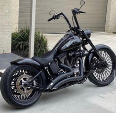 a black motorcycle is parked in front of a garage with its wheels turned to the side