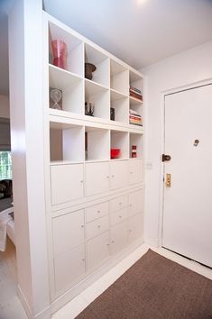 an empty room with white bookcases on the wall and carpeted flooring