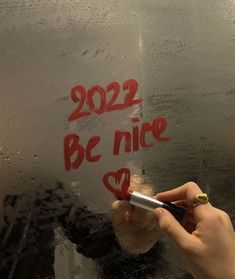 someone writing on the side of a bus with red hearts and words that read, 2012 be nice