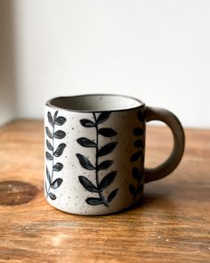 a black and white coffee cup sitting on top of a wooden table