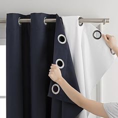 a person is opening the curtains with their hands and pulling them up from the curtain rod