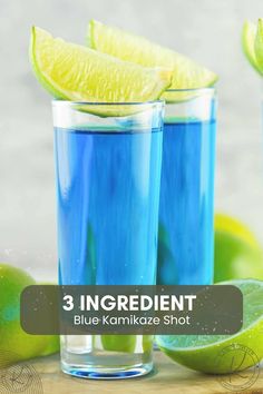 two glasses filled with blue liquid next to limes