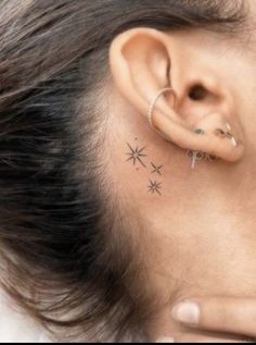 a woman's ear with two small stars on it and one behind the ear