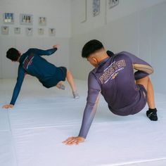 two men are doing push ups on the floor in an empty room with white walls