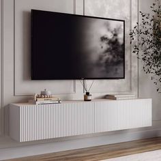 a large flat screen tv mounted to the side of a wall next to a plant