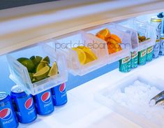 the refrigerator is stocked with soda, lemons, and other foodstuffs in containers