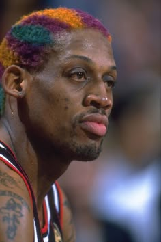 a man with multicolored dreadlocks on his head looking off to the side