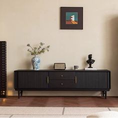 a living room scene with focus on the sideboard and vase in the foreground