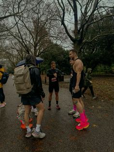 a group of people walking down a road with backpacks on their backs and one man in the middle