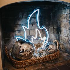 two disco balls sitting on top of a basket next to a fire place in a fireplace