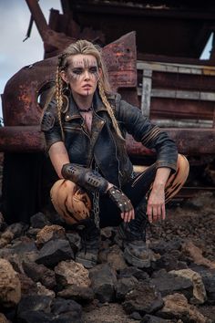 a woman with dreadlocks sitting on rocks in front of an old dump truck