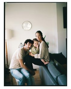 two adults and a child are sitting on a couch