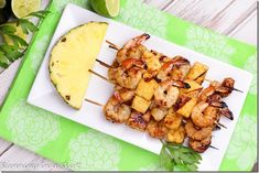 grilled shrimp and pineapple skewers on a white plate with a lime wedge