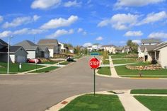 a red stop sign sitting on the side of a road in front of some houses