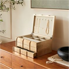 an open wooden jewelry box sitting on top of a dresser