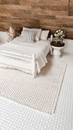 a white bed sitting next to a wooden wall