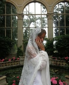 a woman in a white wedding dress is talking on her cell phone while wearing a veil