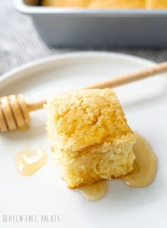 a piece of cake sitting on top of a white plate next to a honey drizzle