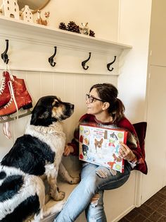 a woman sitting next to a dog holding a box