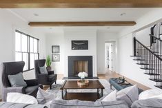 a living room filled with furniture and a fire place in front of a stair case