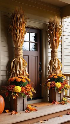 two scarecrows made out of pumpkins and corn stalks on the front porch