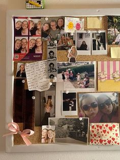 a bulletin board covered in photos and magnets with pink ribbon attached to the back