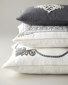 four pillows stacked on top of each other in different colors and patterns, all with decorative embroidered details