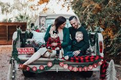 a man and woman sitting in the back of a pickup truck with their baby boy