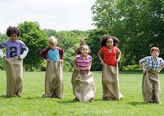 four children standing in the grass with their backs turned to look like they're ready for something