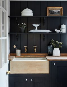 a kitchen with black painted walls and wooden counter tops, gold faucets and brass fixtures