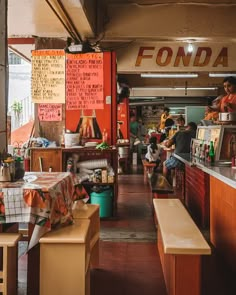 the inside of a restaurant with lots of food on tables and people sitting at their desks