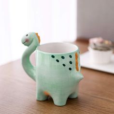 a green ceramic mug with an animal design on it