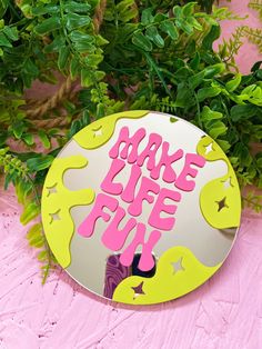 a mirror with the words bake life fun painted on it next to some plants