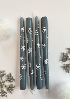 three candles with snowflakes on them next to christmas decorations