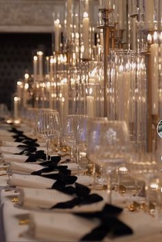 a long table with many wine glasses and candles on the top one is lined up