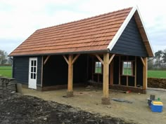 a black house with a red roof and white trim on the front door is being built